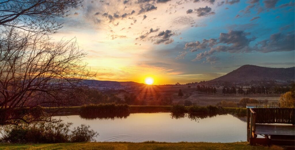 Solnedgang over landskap med fjell og vann