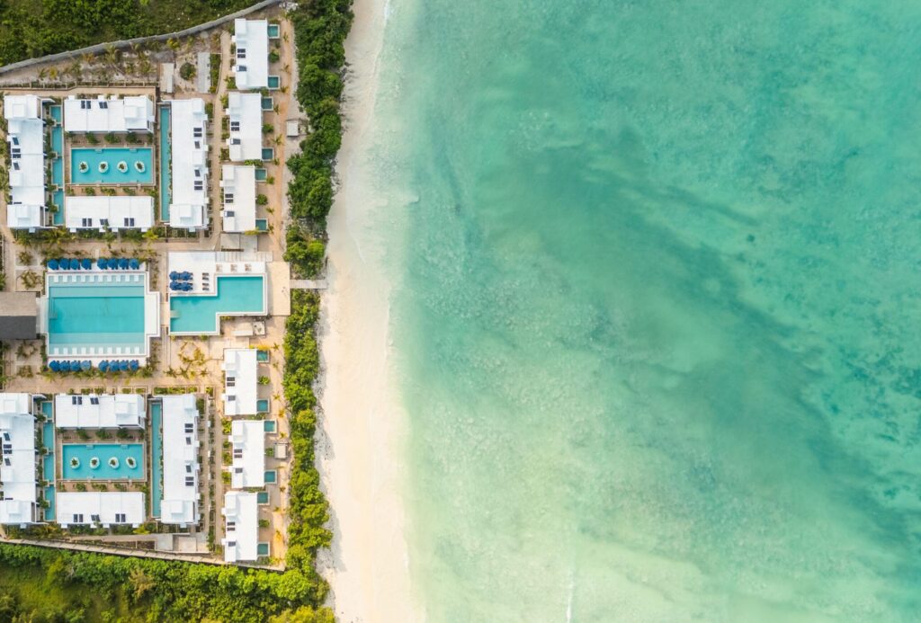 Hvit strand med palmer langs kanten ved turkist hav på Zanzibar