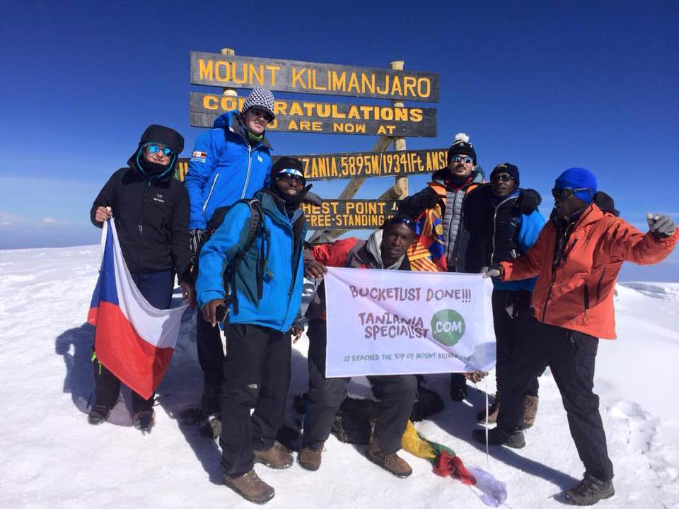En gruppe mennesker står foran Mount Kilimanjaro-skilt