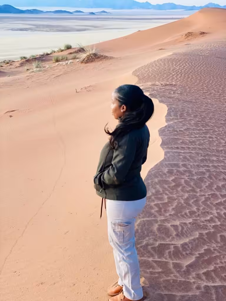 Anna står på en sanddyne og speider utover ørkenen i Namibia